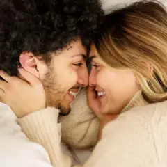 Coppia in un abbraccio intimo, sorrisi e sguardi complici. Un momento di tenerezza e sesso a coppia che celebra l'amore.
