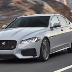 Srebrny Jaguar XF pędzi po pustynnej drodze. Czy jaguar xf jest drogi w utrzymaniu? To pytanie zadaje sobie wielu miłośników tej marki.