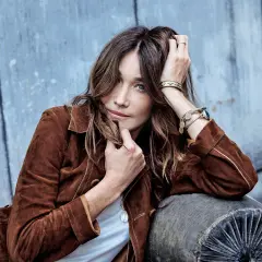 Carla Bruni joven, con su melena suelta y mirada penetrante, posa con una chaqueta de ante marrón.