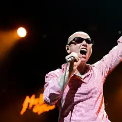 Sinéad O'Connor na koncercie, z ręką w górze, śpiewa swoje legendarne utwory.