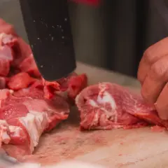 Przygotowanie karkówki do peklowania na wędzenie. Mięso jest krojone na desce.