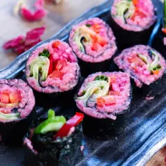 Sushi rolls with vibrant pink rice, filled with fresh vegetables like cucumber and red pepper. A delightful pink rice recipe for a colorful meal.