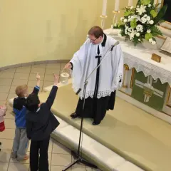 Dzieci na nabożeństwie w kościele luterańskim. Ksiądz z kadzielnicą błogosławi zgromadzonych.