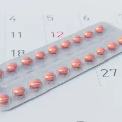 Blister z różowymi tabletkami antykoncepcyjnymi leży na kalendarzu, symbolizując różne rodzaje tabletek antykoncepcyjnych i planowanie.
