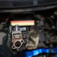 Zardzewiały zawór EGR w dłoni mechanika, gotowy do montażu w silniku.