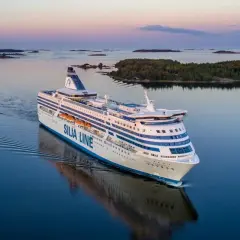Prom Silja Line płynie przez spokojne morze, tworząc fale. Widok na wyspy i zachodzące słońce. Podróż z Tallinna do Helsinek.