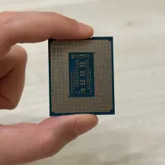 Un dedo sostiene un microprocesador, mostrando su intrincado diseño de pines dorados y el chip central.