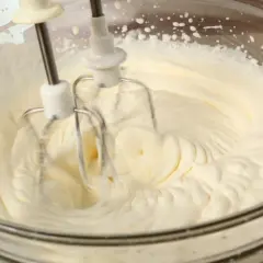 Ubity krem śmietankowy do tortu bez mascarpone, przygotowywany mikserem w szklanej misie.