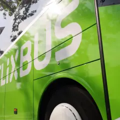 Zielony autobus FlixBus z białym logo, widok z boku.