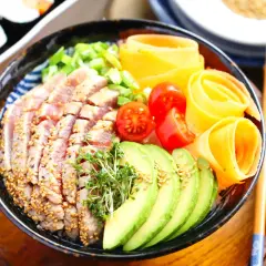 Ein bunter Chirashi Bowl mit Thunfisch, Avocado, Tomaten und Karottenröllchen.