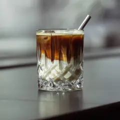 Eiskaffee selber machen ohne Vanilleeis: Ein Glas mit geschichtetem Kaffee und Milch, garniert mit einem Metallstrohhalm.