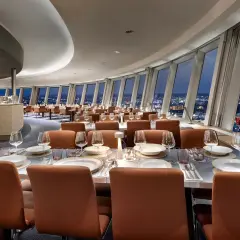Elegant restaurang Berlin med utsikt över staden. Vackert dukade bord med glas och tallrikar. Vinhylla i bakgrunden.