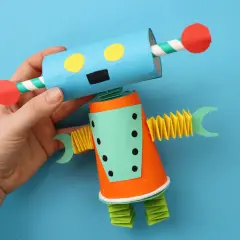 Ein bunter Roboter, der zum **Roboter basteln** einlädt. Er hat einen blauen Kopf mit gelben Augen und einen orangefarbenen Körper.