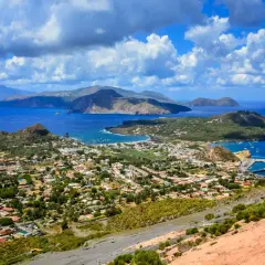 Panoramica mozzafiato delle isole Eolie, tra le isole più belle della Sicilia, con case bianche, vegetazione lussureggiante e mare blu intenso.