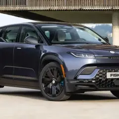 Fisker Ocean, un SUV eléctrico azul oscuro, aparcado frente a una casa moderna con vistas a un bosque.