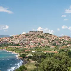 Widok na malowniczą wioskę z zamkiem na wzgórzu, turkusowe morze i zielone wzgórza. Lesbos atrakcje zachwycają!