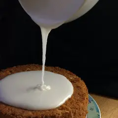 Ein cremiger zuckerguss mit milch fließt auf einen Kuchen.