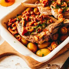 Un plat de viande blanche savoureux, des côtelettes de porc rôties avec des pommes de terre et des girolles, garni de persil frais.