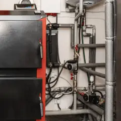 Kotłownia z piecem i skomplikowaną instalacją hydrauliczną. Widoczna wentylacja w kotłowni zapewnia bezpieczeństwo.