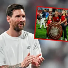 Lionel Messi, najbardziej utytułowany piłkarz w historii, uśmiecha się, podczas gdy w tle widać jego drużynę świętującą z pucharem.
