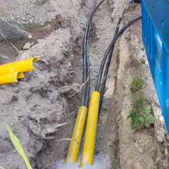 Kabel elektryczny w ziemi, chroniony żółtymi osłonami, przygotowany do zakopania zgodnie z przepisami.