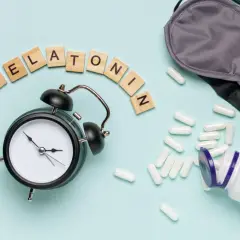 Budzik, maska na oczy i kapsułki z napisem "Melatonina" sugerują pytanie: czy melatonina jest bezpieczna?