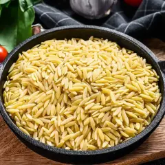 Czarny garnek pełen makaronu w kształcie ryżu, gotowy na pyszne danie.