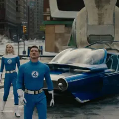 Fantastyczna Czwórka w swoich niebieskich strojach stoi obok futurystycznego pojazdu. Recenzja filmu zapowiada emocjonującą przygodę.