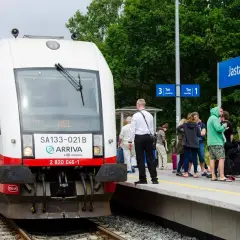 Pociąg Arriva z napisem "HEL" na stacji Jastarnia, gotowy do podróży z Gdańska na Hel. Ludzie czekają na peronie.