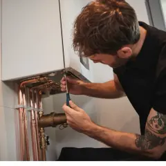 Un technicien ajuste une chaudière. Attention, trop de pression chaudière dangereux.
