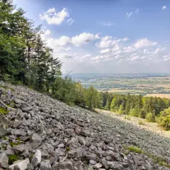 Kamieniste zbocze Gór Świętokrzyskich z widokiem na dolinę i lasy.