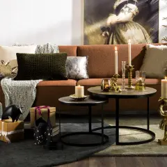 Salon chaleureux avec canapé rouille, coussins texturés et décorations dorées. L'ambiance est réconfortante, avec des touches de **couleur cooper** apportées par des bougies et des statuettes d'éléphants.
