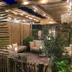 Gemütliche Gartenoase mit rustikalen Holzbalken, Lichterketten und bequemen Sitzgelegenheiten. Tolle Holzbalken Ideen für Gartenmöbel und Deko.