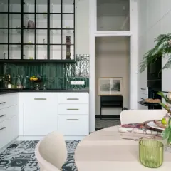 Nowoczesny pomysł na kuchnię: białe szafki, zielone kafelki, czarny okap i stylowe dodatki.