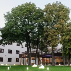 Nowoczesny budynek Teodorka Med & Spa otoczony zielenią i oświetlony lampkami.
