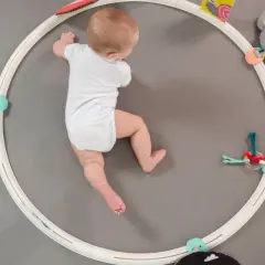 Neonato di 6 mesi esplora giochi appesi a un cerchio, stimolando i suoi primi esercizi e movimenti.