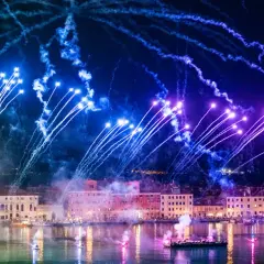 Pokaz fajerwerków nad kanałem w Wenecji z łodziami i budynkami w tle.