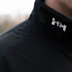 Czarna kurtka z białym logo HH. Helly Hansen to firma znana z odzieży outdoorowej i żeglarskiej.