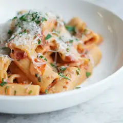 Pyszne rigatoni w kremowym sosie pomidorowym, posypane parmezanem i natką pietruszki. Idealny przepis na szybki obiad.