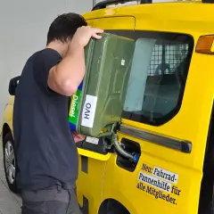 Uomo versa diesel paraffinico da tanica verde in un furgone giallo.