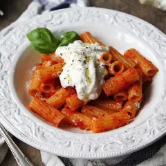 En krämig burrata pasta med rigatoni i tomatsås, toppad med färsk basilika och svartpeppar.