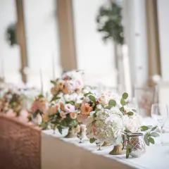 Magnifique centre de table floral pour un mariage, avec des roses pâles et des hortensias blancs. Une bougie mariage subtile complète la scène.