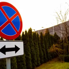 Znak zakazu parkowania przed znakiem z dwoma strzałkami informuje, że postój jest zabroniony po obu stronach.