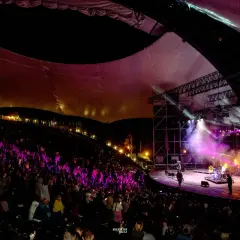 Koncert na amfiteatrze w Mrągowie, oświetlona scena i publiczność.