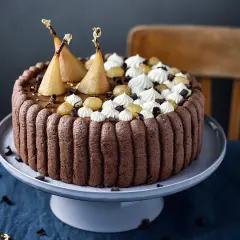 Charlotte poire chocolat, un gâteau élégant avec des poires pochées dorées, de la crème fouettée et des éclats de chocolat.