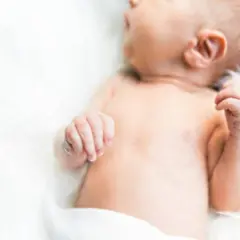 Delikatna skóra niemowlęcia, być może zmagającego się z trądzikiem niemowlęcym lub skazą białkową, otulona bielą.