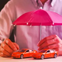 Due macchinine arancioni sotto un ombrello rosa. Capire la **legge Bersani assicurazione come funziona** è fondamentale per proteggere il tuo veicolo.
