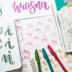 Piękne **graffiti letters** ozdabiają zeszyty. Widać napisy "maj", "wiosna" oraz litery "kwiecień" w zielonej kaligrafii.