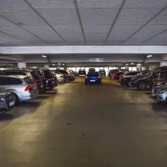 Un garaje lleno de coches, con un coche azul en el centro. Los gastos de compra de garaje son altos.
