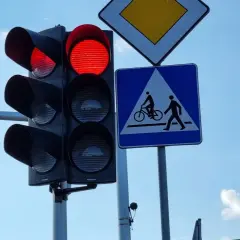Czerwone światło na sygnalizatorze drogowym, obok znak d6 informujący o przejściu dla pieszych i rowerzystów.
